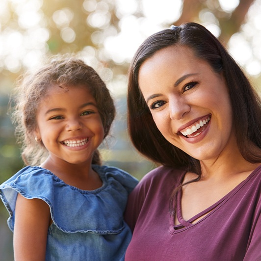 Mother holding young daughter and smiling