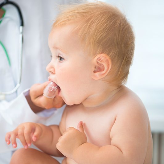 Dentist helping baby do stretches after lip and tongue tie treatment