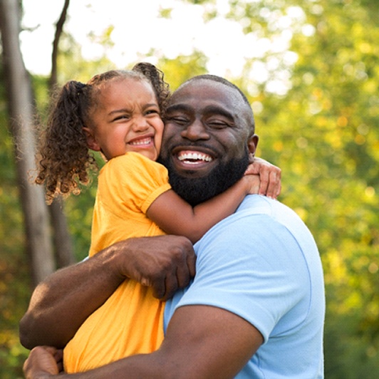 A dad holding onto his daughter and smiling while in Phillipsburg