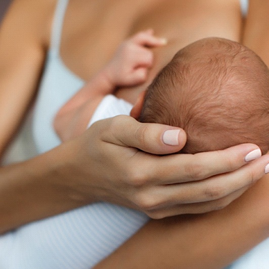 An up-close image of a woman holding her baby’s head while breastfeeding in Phillipsburg