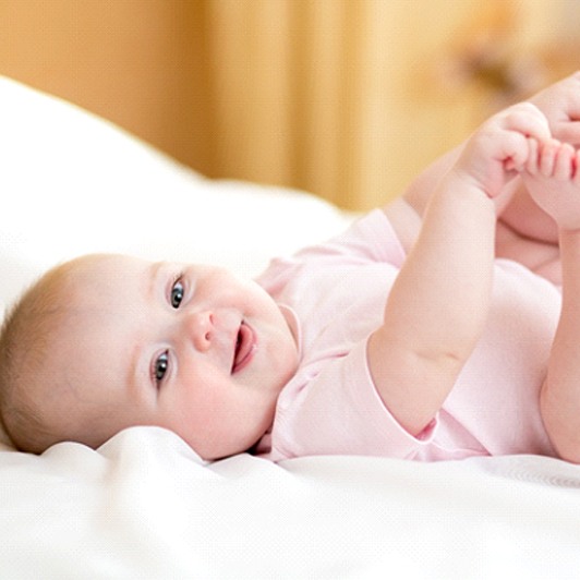 Happy baby lying on a bed in Phillipsburg