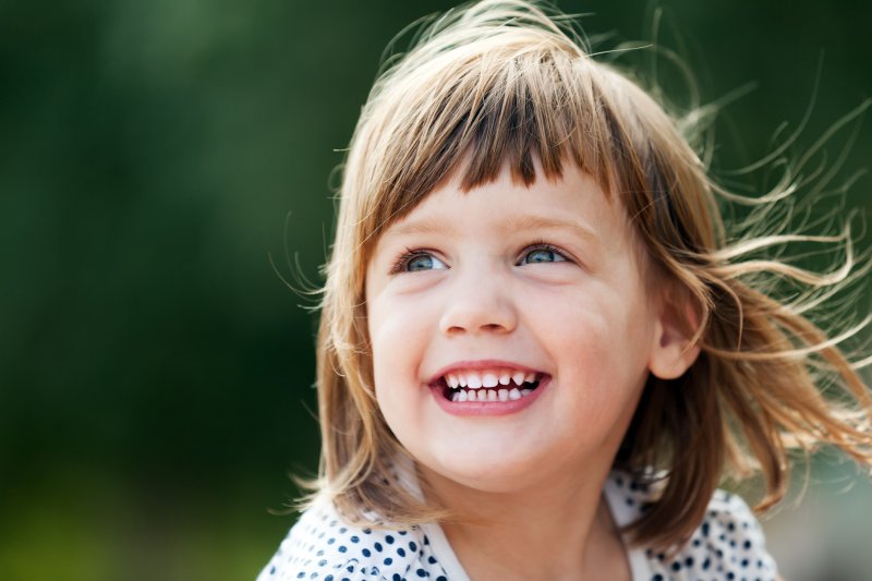 a little girl playing outside and showing off her healthy smile