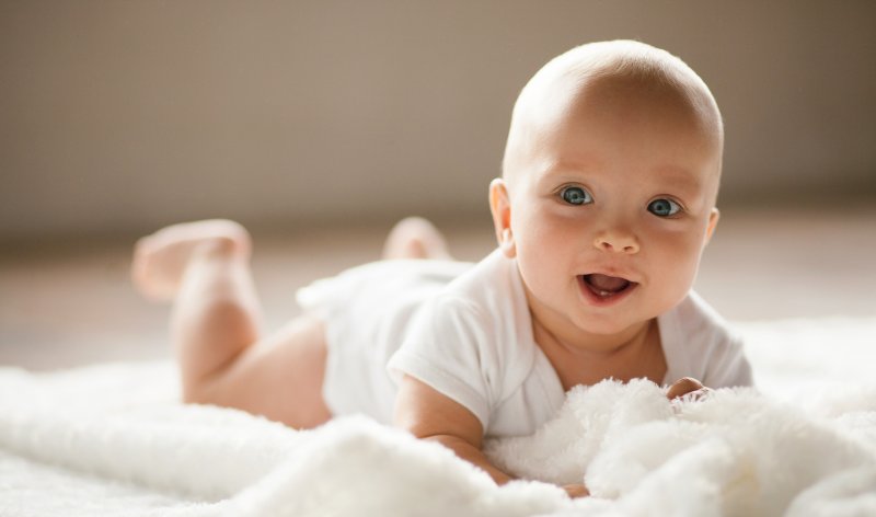 baby smiling while on its stomach 