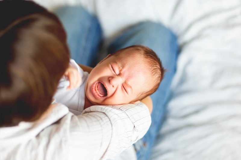 A parent holding a crying baby 