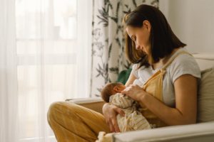 a parent sitting in a chair and breastfeeding their infant