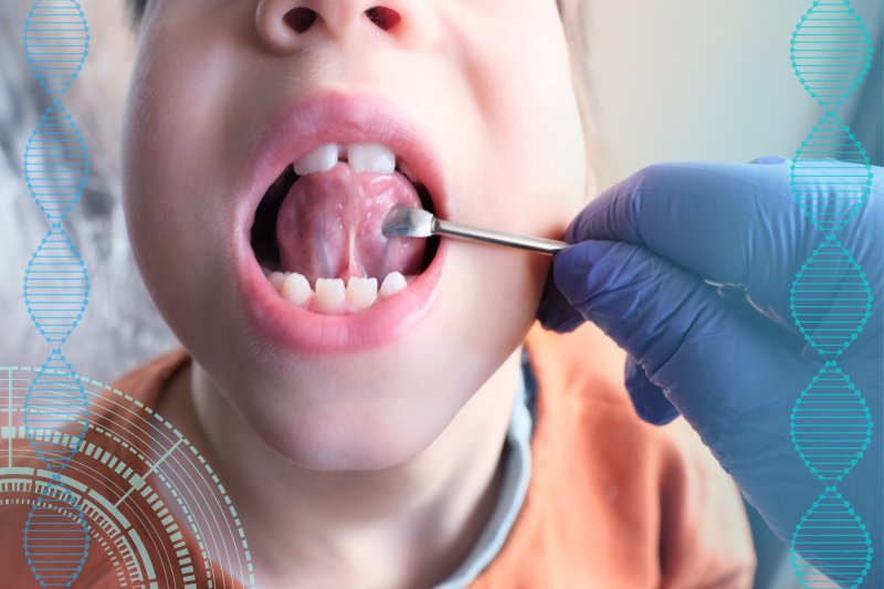 A dentist opening a young patient’s mouth to demonstrate a lip or tongue tie