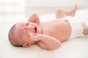 Fussy infant lying on bed