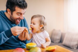 Father and child eating a mango